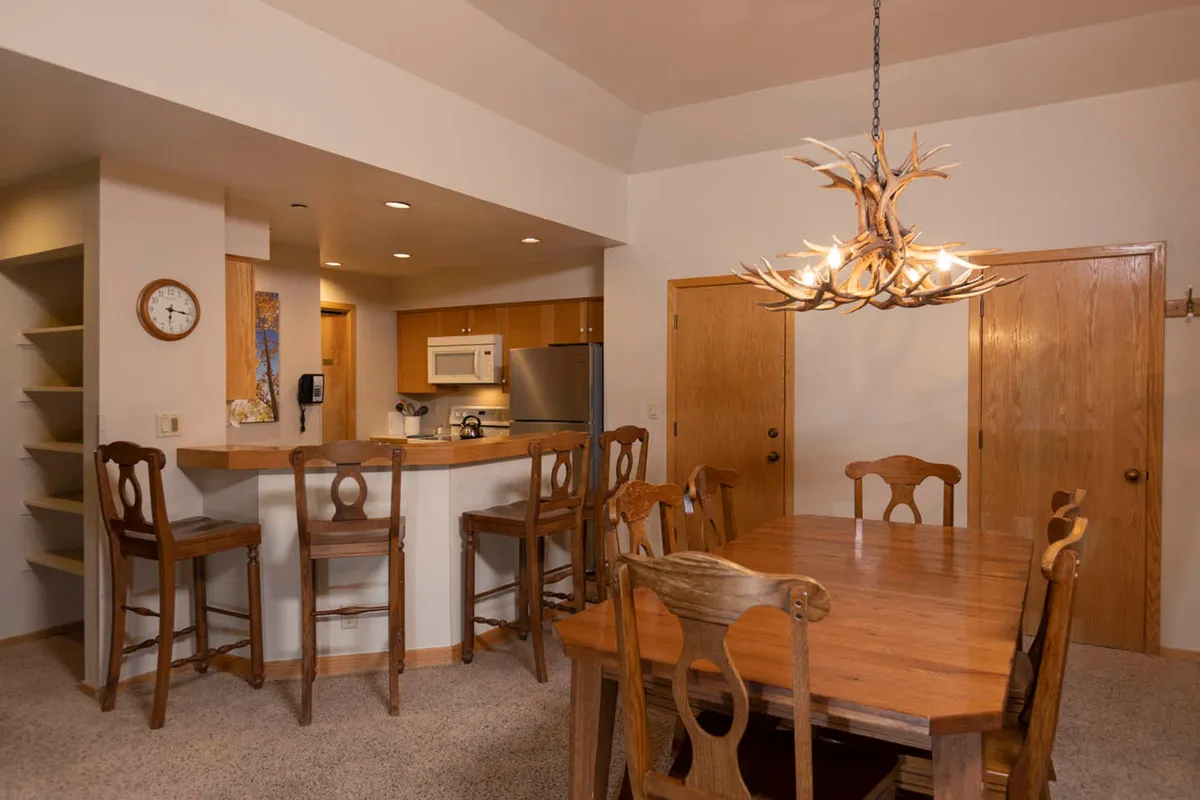 The image showcases a beautifully lit, open-concept dining area with a stylish chandelier above a spacious table, seamlessly connected to a modern kitchen bar. The inviting setup is ideal for family meals, holiday celebrations, and social gatherings, all framed by a warm, welcoming ambiance that hints at memorable moments shared together.